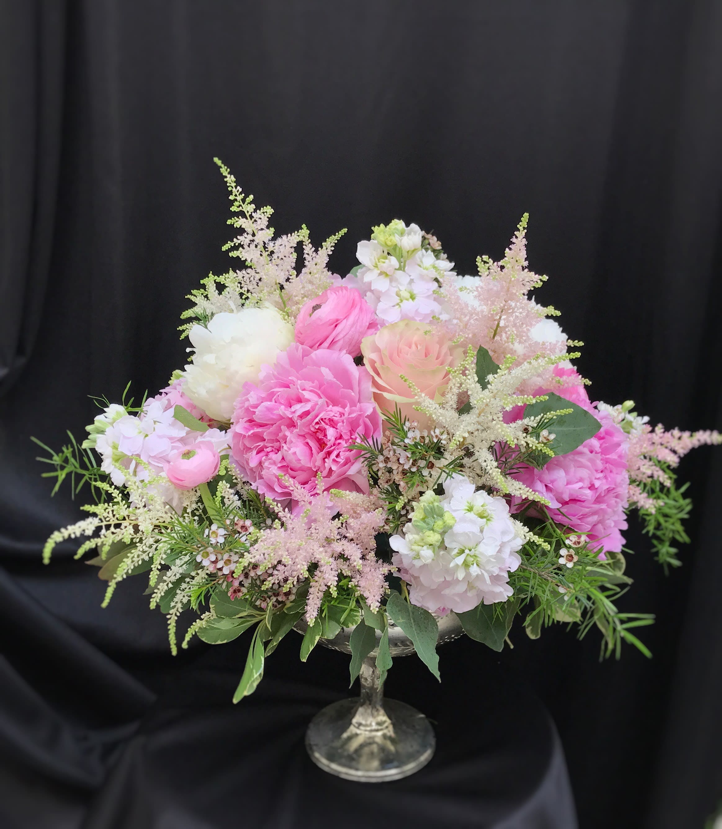 Pink and white floral arrangement in a glass pedestal vase