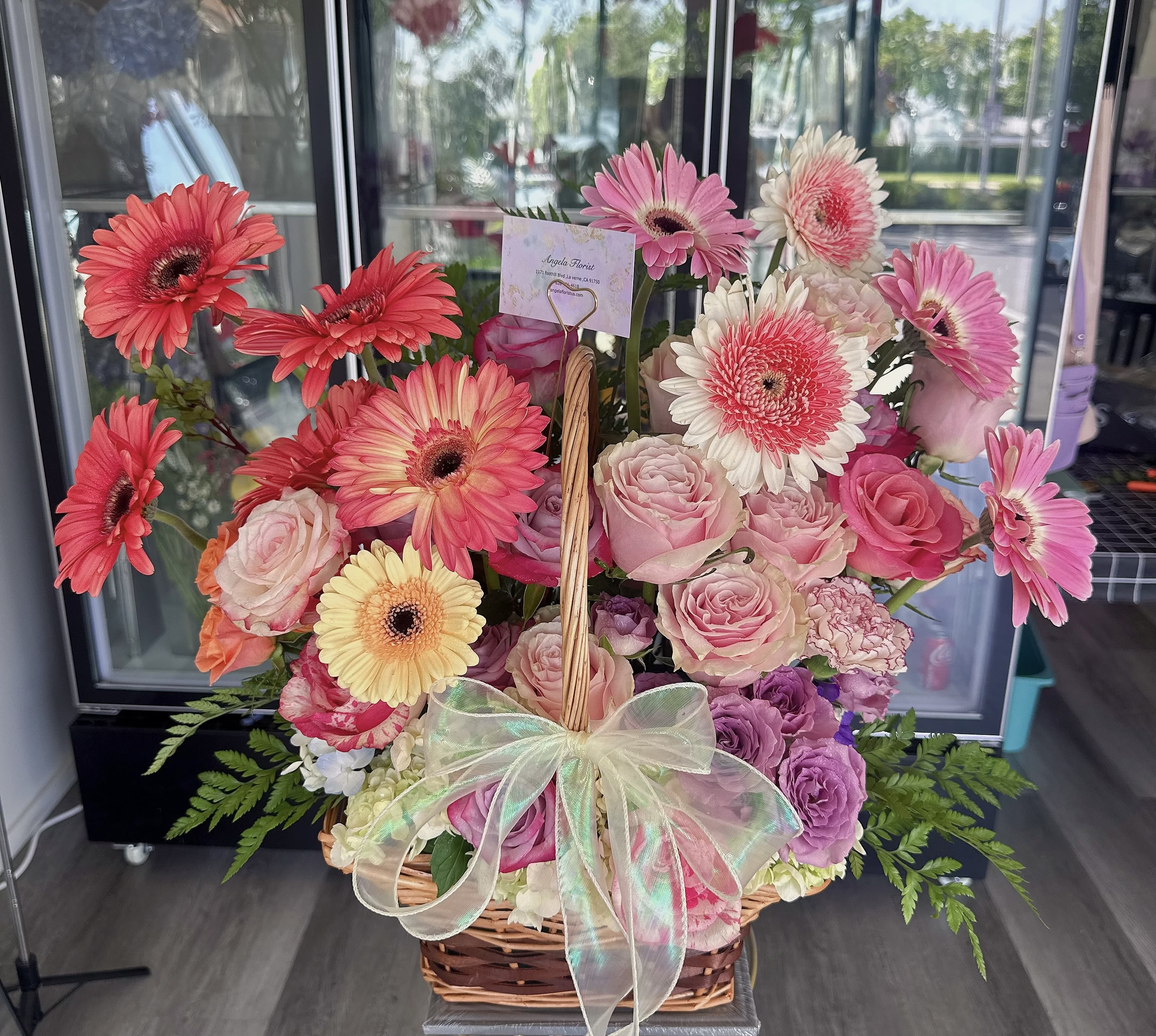 Basket arrangement of pink gerberas and roses with a sheer bow