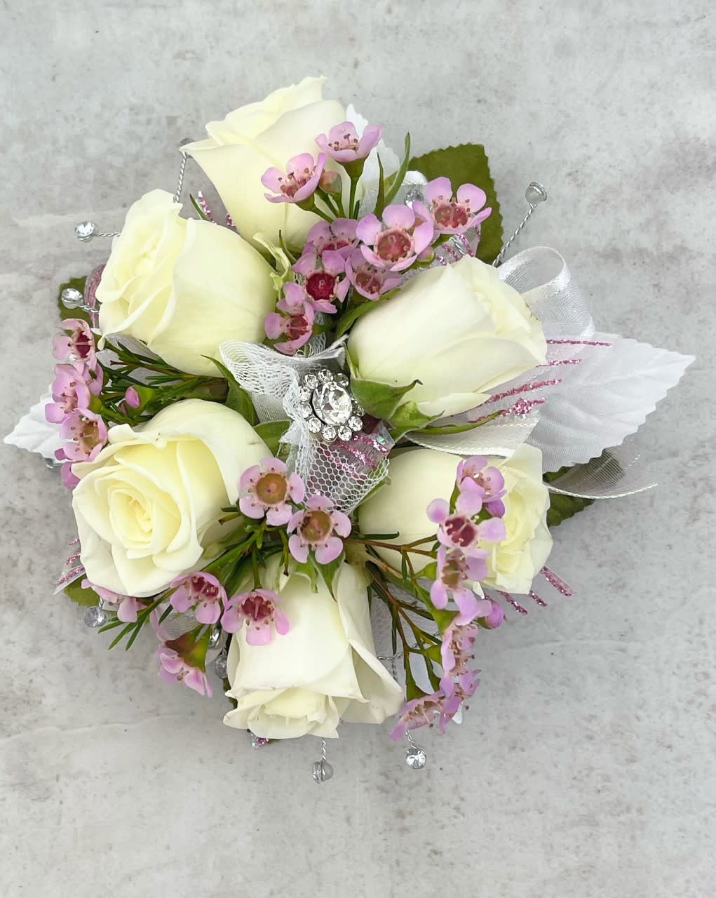 White rose bouquet with pink accent flowers and a jeweled ribbon