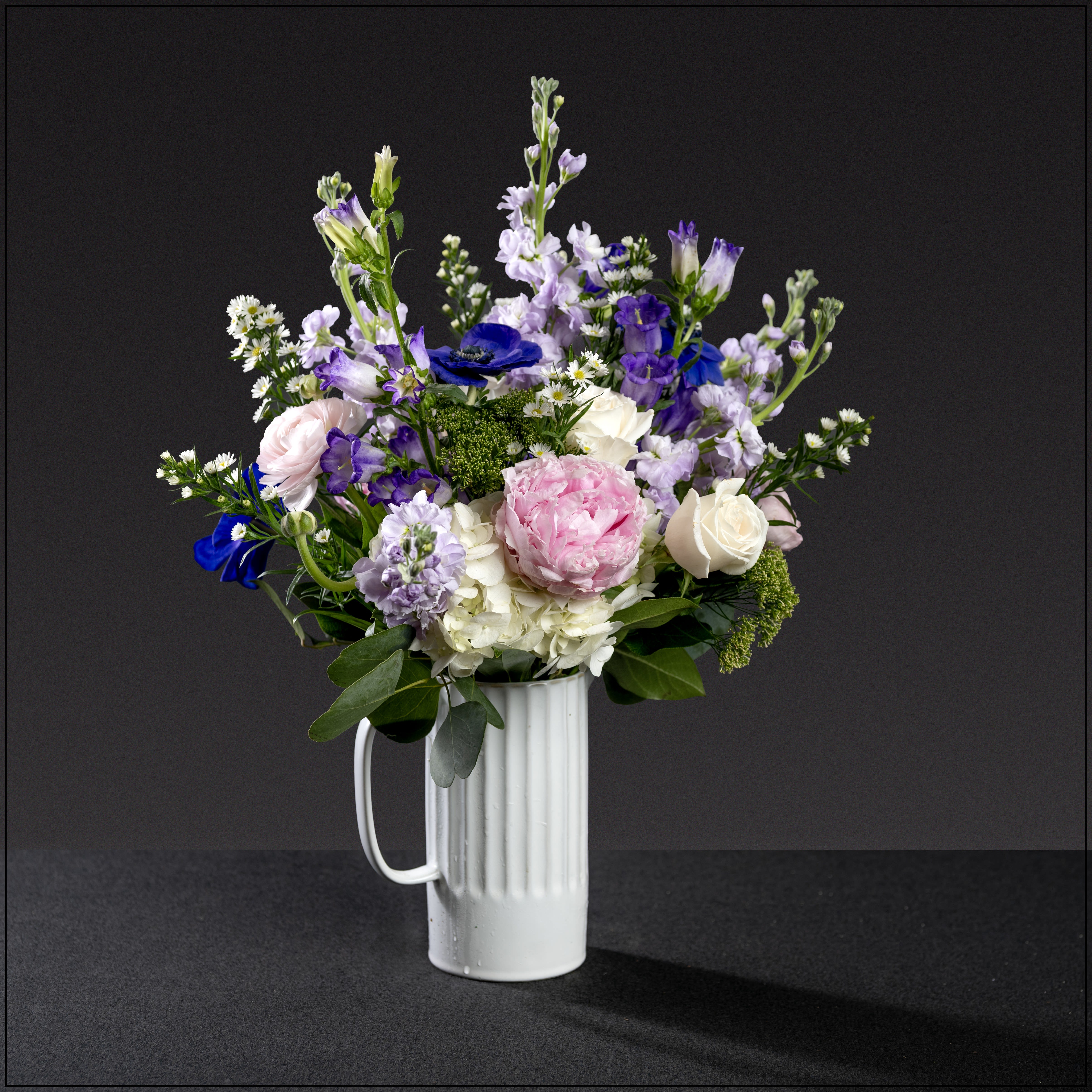 Loved Beyond Words - A stylish white pitcher filled with all of the favorite flowers; hydrangea, fragrant stock, campanula, roses, anemones, ranunculus, asters, trachelium, and peonies. Approximately 24" tall and 17" wide.