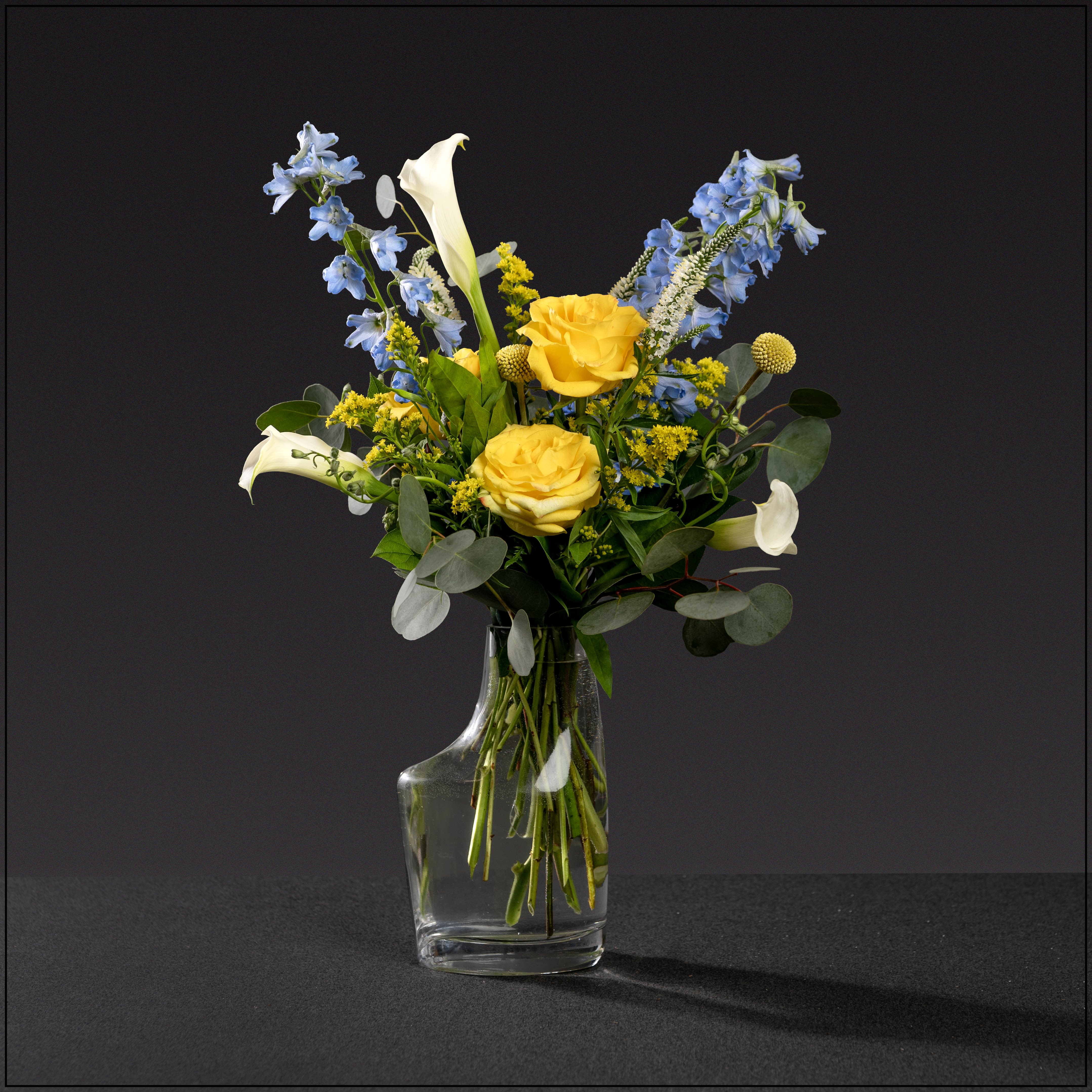 Violin - Uniquely shaped vase filled with delphinium, roses, miniature calla lilies, veronica, and solidago