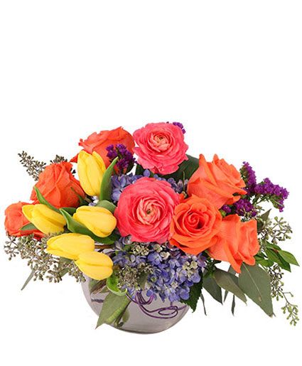 Jewel in Bloom - This vibrant floral arrangement is a high-energy mix of bright spring colors and rich textures. It's compact, rounded, and brings a "wow" factor to any space.