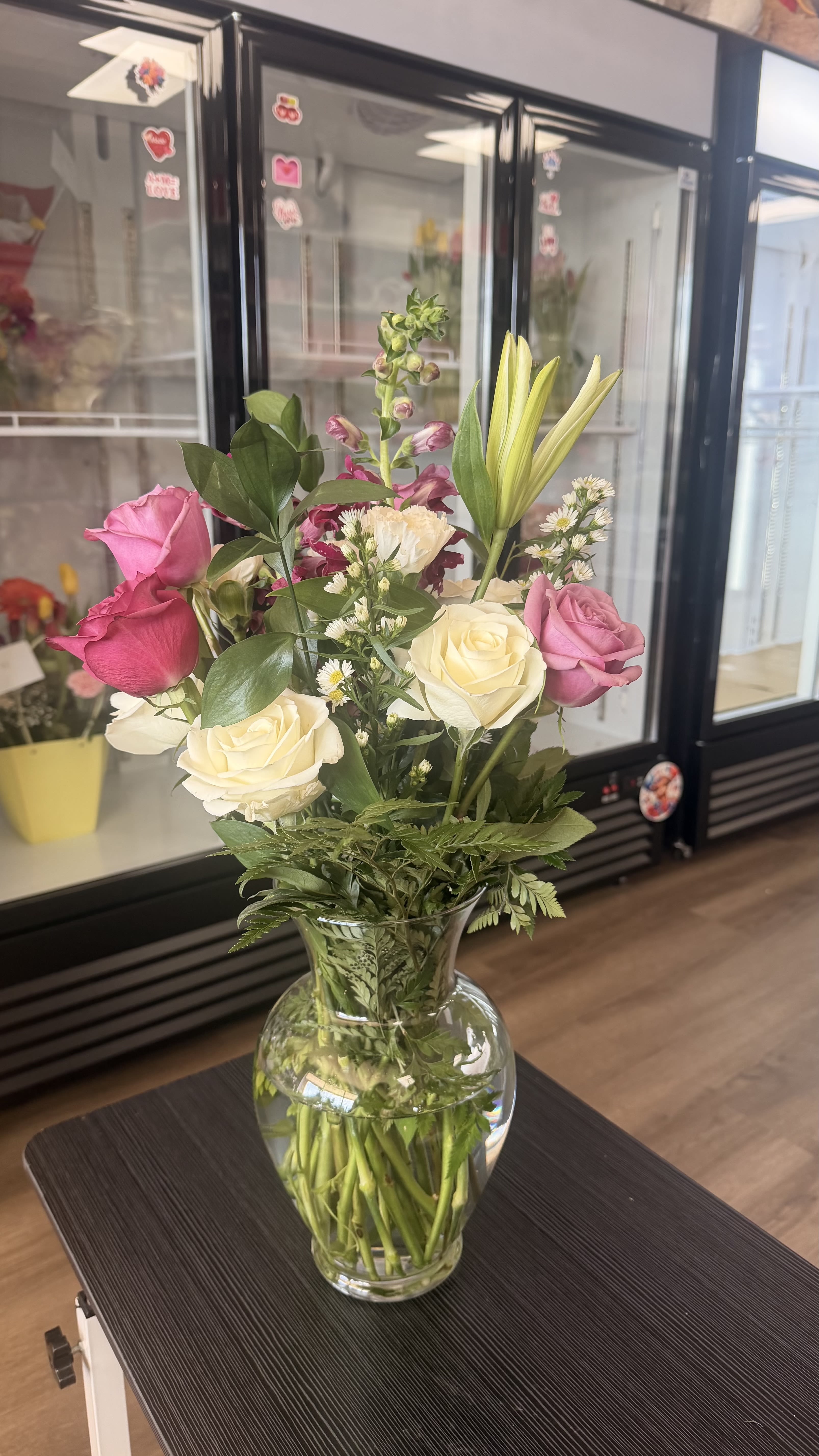 Mixed bouquet of pink and white roses with lilies and other flowers in a clear glass vase