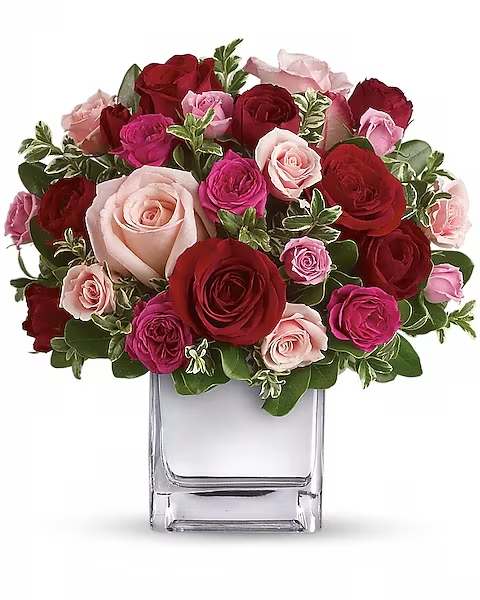 Bouquet of red, pink, and blush roses in a clear glass vase