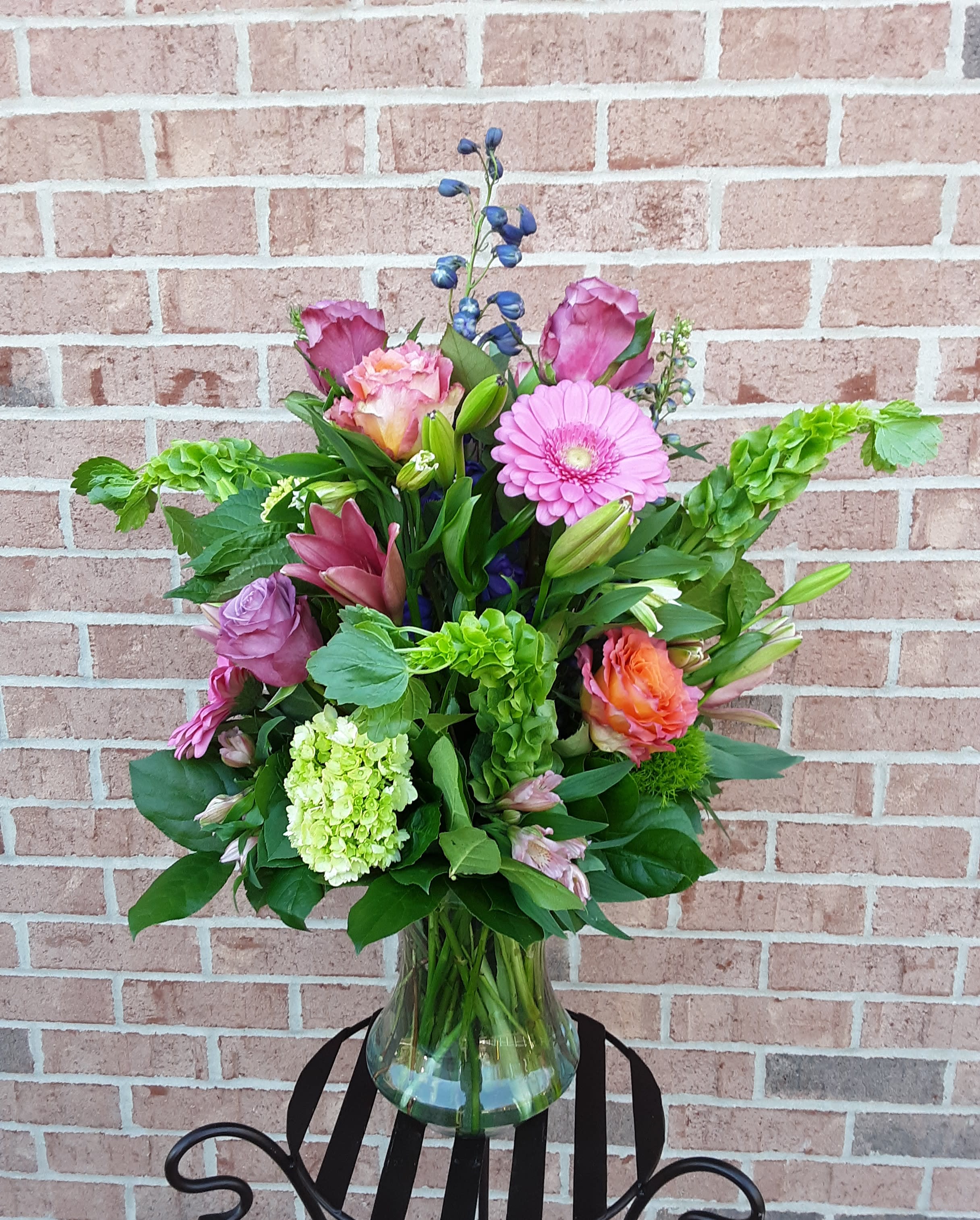 Mixed bouquet in a clear glass vase with pink, purple, and green blooms