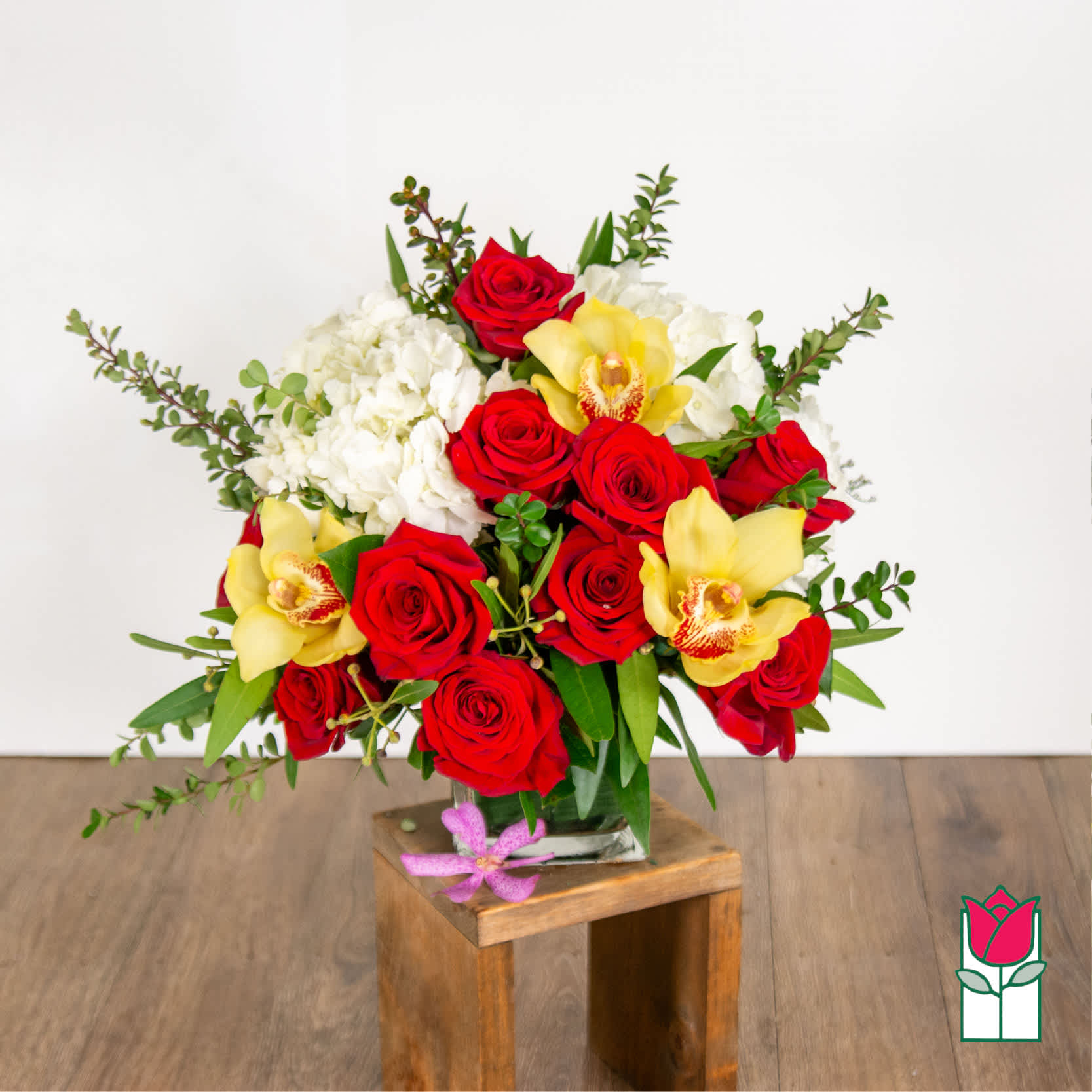 Bouquet of red roses, white hydrangeas, and yellow orchids in a glass vase