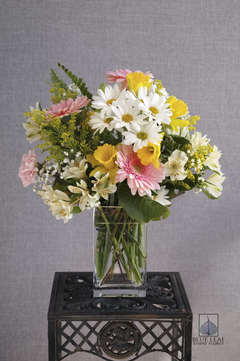 Mixed bouquet of daisies, gerbera daisies, and alstroemeria in a glass vase