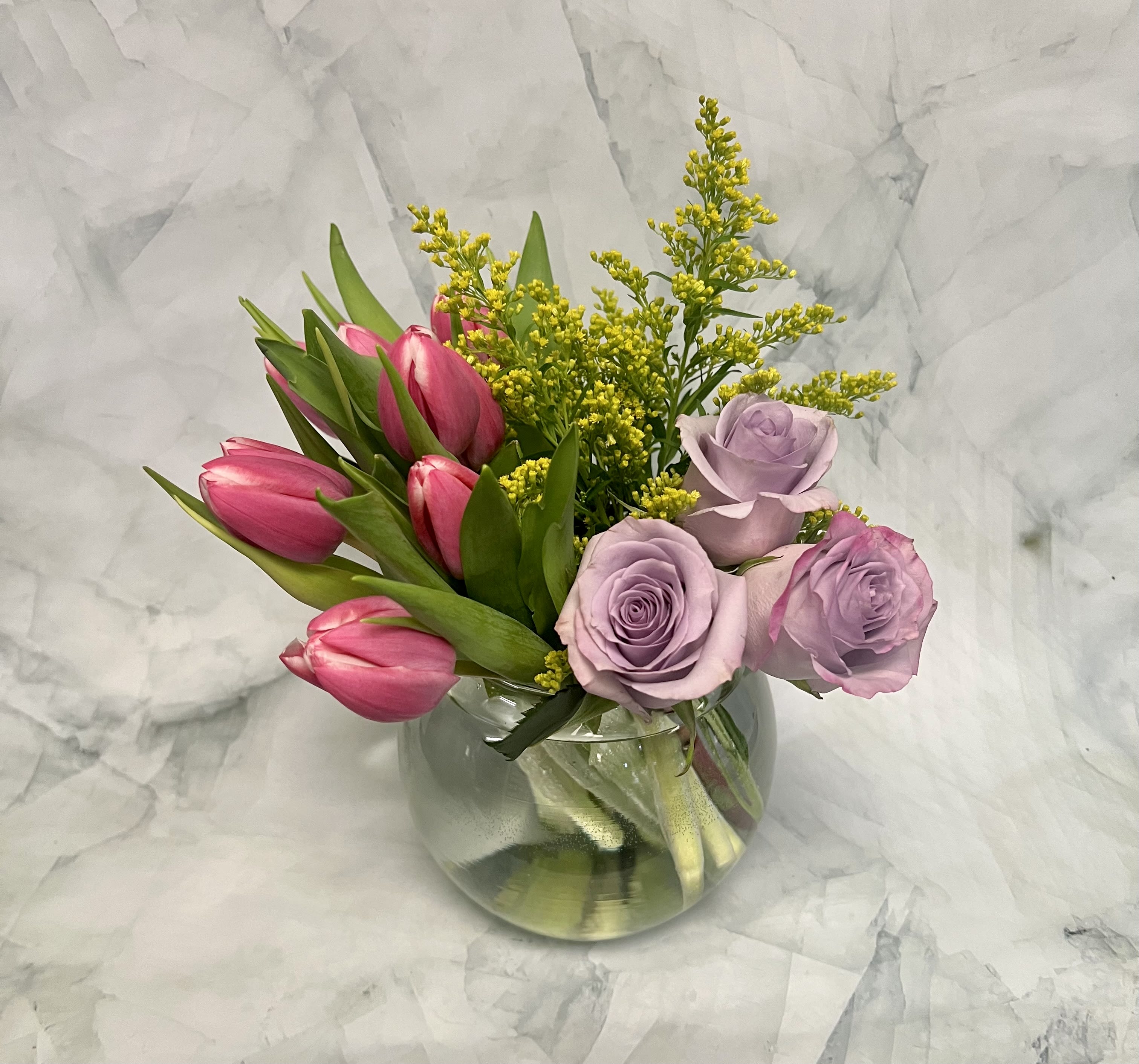 Pink tulips and lavender roses in a clear glass vase