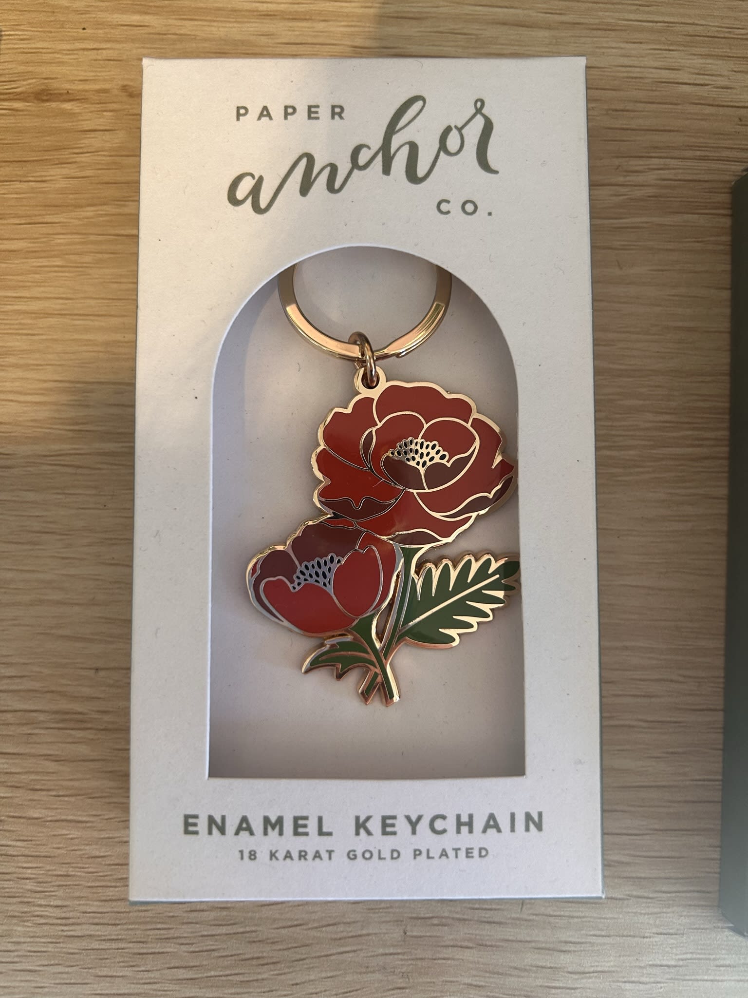 Red floral enamel keychain in a white retail box