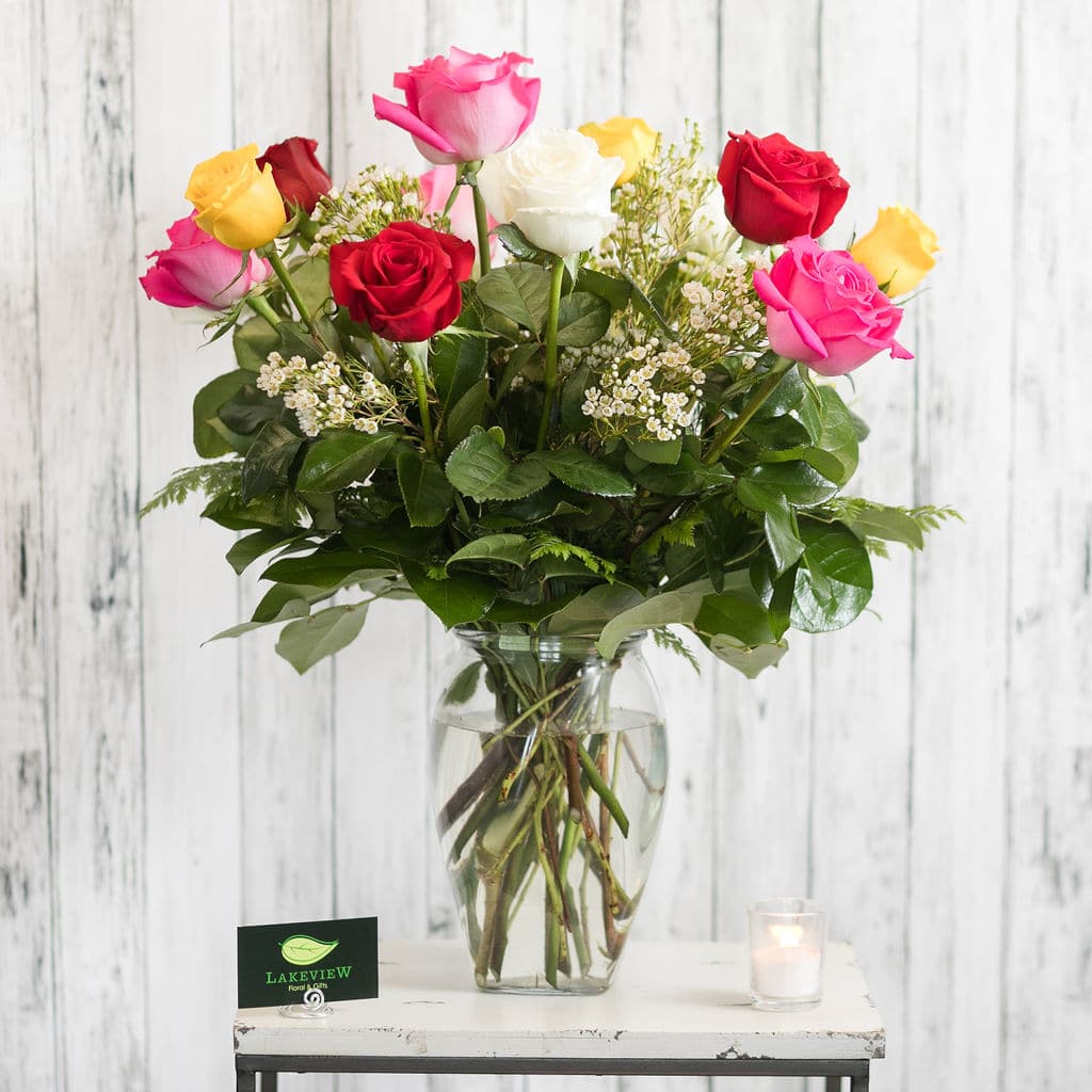 Mixed roses in a clear glass vase with a small candle beside it