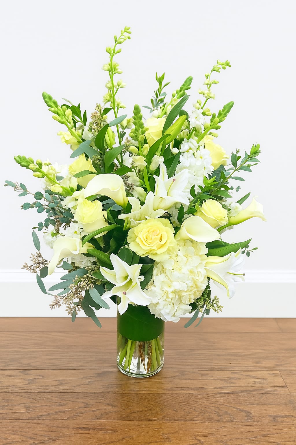 White and pale yellow floral arrangement in a glass vase