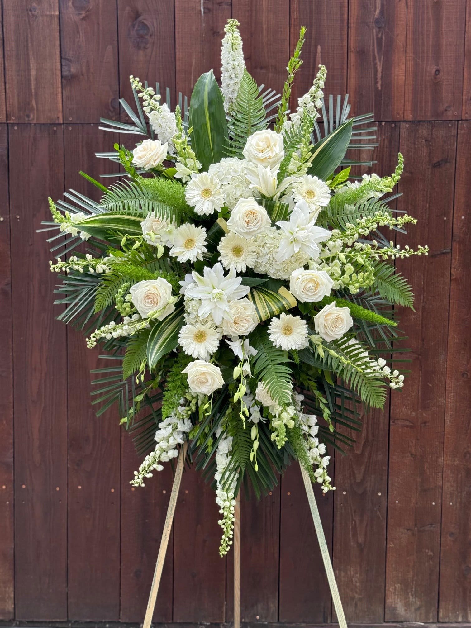 White floral standing spray with roses and lilies on an easel