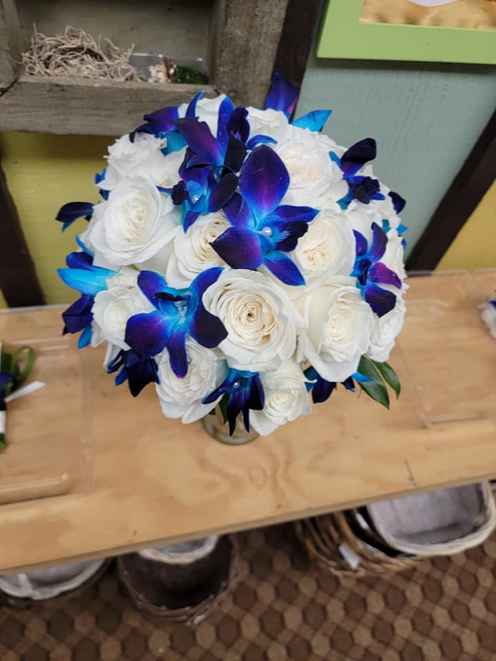 White rose bouquet with vivid blue-purple orchids in a small vase