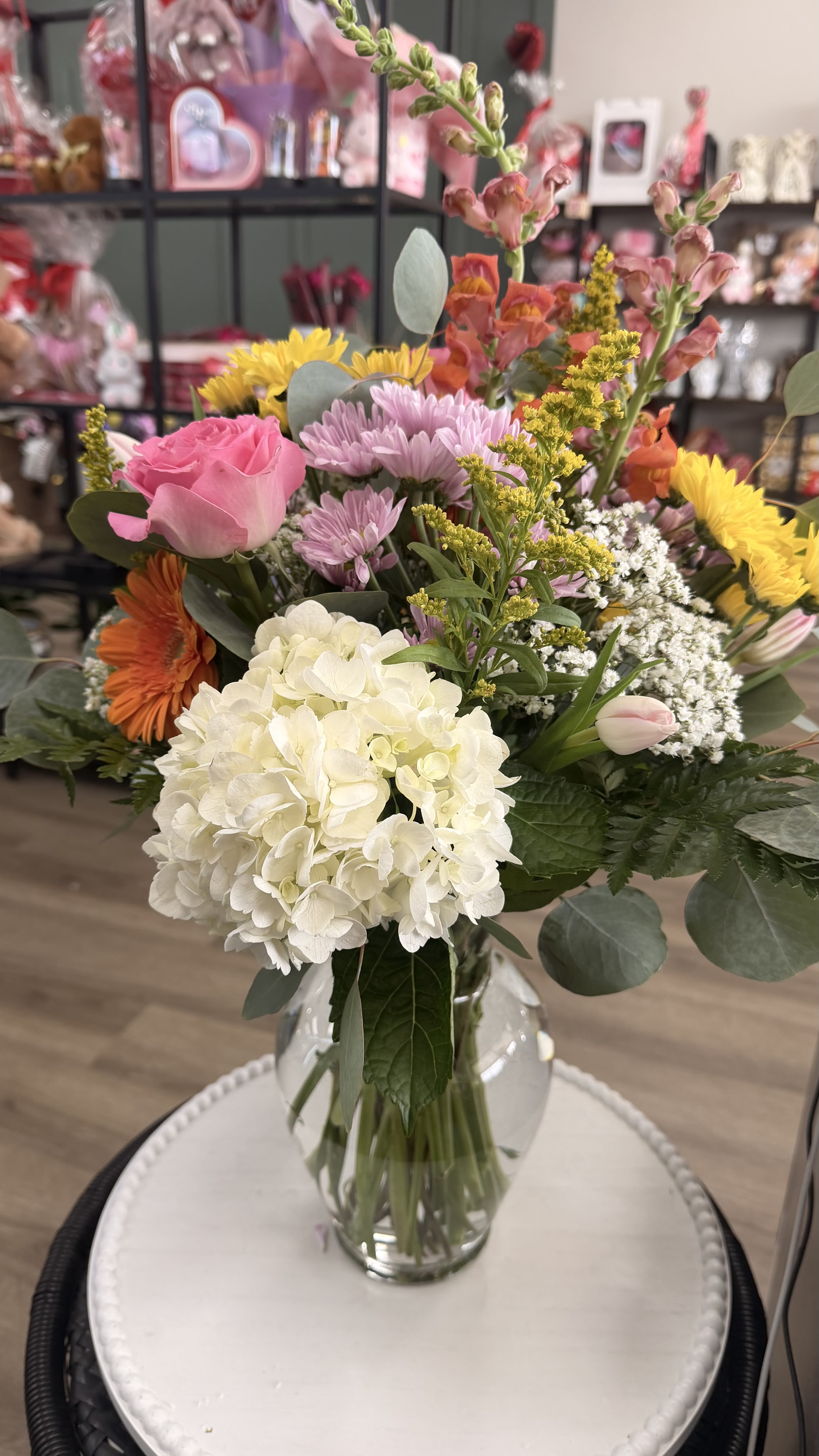 Mixed bouquet in a clear glass vase with pink, white, yellow, and orange flowers