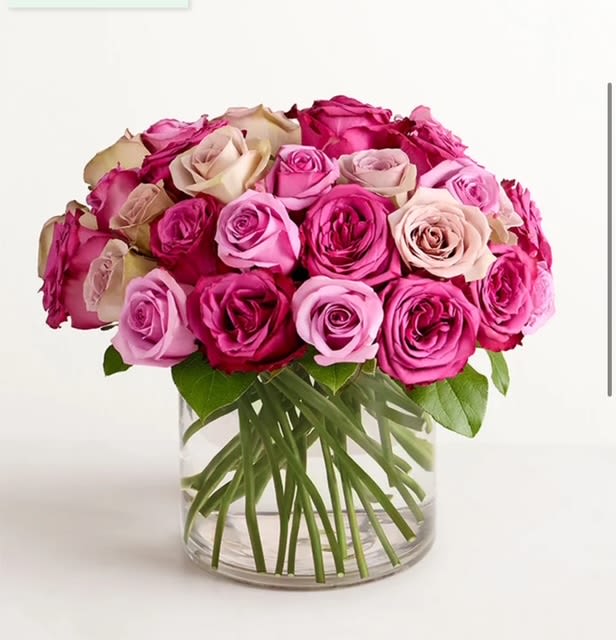 Pastel Harmony - A delicate flower arrangement in a clear glass vase features an elegant blend of pastel-shaded roses, creating a soft and romantic atmosphere.