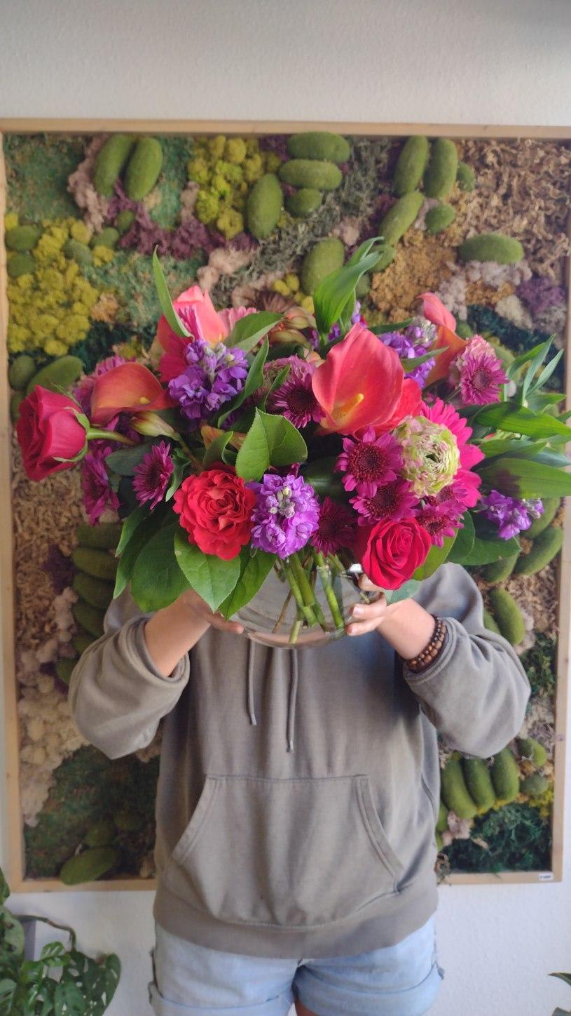 Large mixed bouquet of pink, purple, and orange flowers in a glass vase