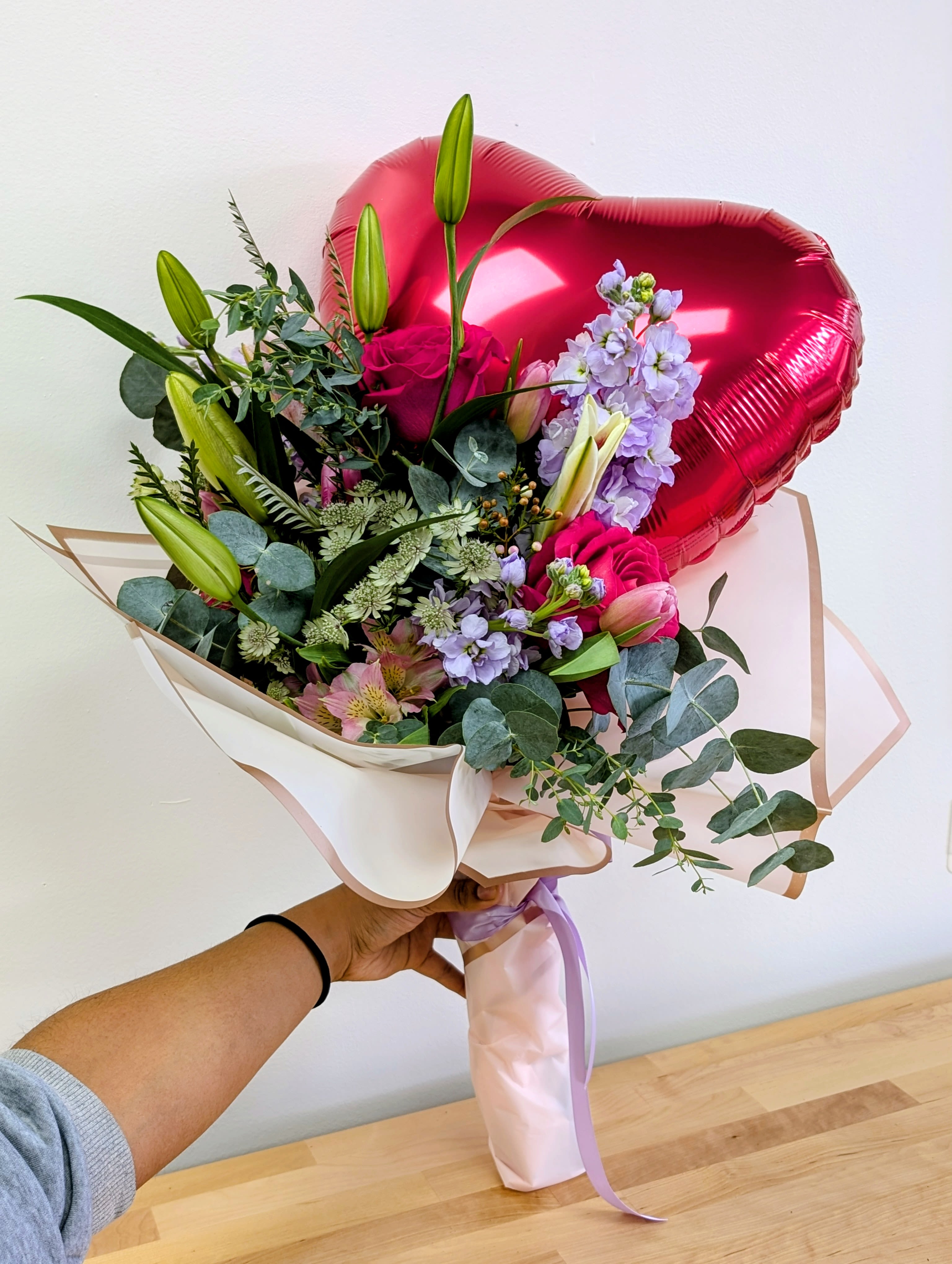Bouquet of pink roses and lilies with a red heart balloon