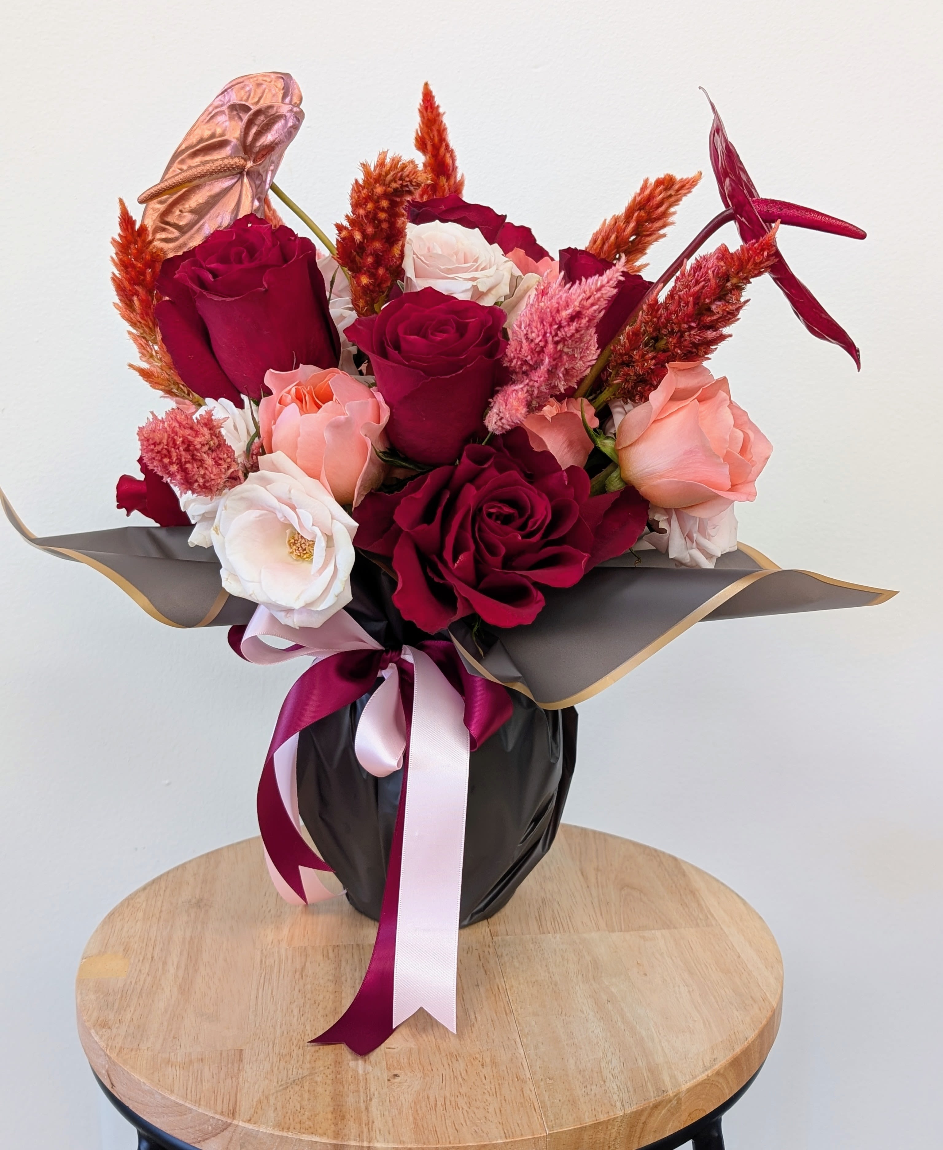 Bouquet of red, pink, and white roses in black wrap with ribbon