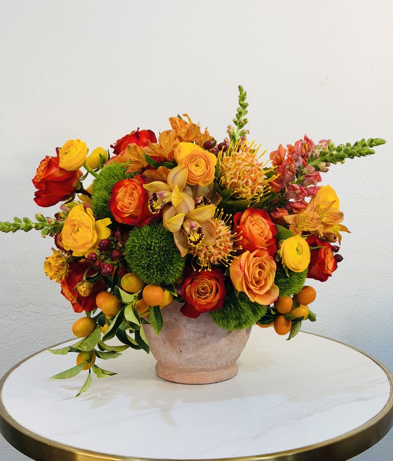 Golden Sunset Bloom - Experience the warmth and vibrancy of our Golden Sunset Bloom, a stunning floral arrangement designed with rich orange, golden yellow, and deep red tones. Featuring premium roses, exotic textures, and seasonal blooms, this design is beautifully accented with fresh kumquats (mini citrus fruits), adding a unique, vibrant, and luxurious touch. Arranged with fresh greenery and artistic detail, this piece creates a bold and unforgettable statement. Perfect for birthdays, celebrations, thank-you gifts, or simply to brighten someone’s day, this arrangement delivers both elegance and charm. Each piece is handcrafted at Guy Floral Studio with attention to detail and a passion for floral artistry. We proudly offer same day flower delivery in West Hollywood, Beverly Hills, Bel Air, Beverly Grove, Santa Monica, Culver City, Hollywood Hills, Hollywood, and surrounding Los Angeles areas.