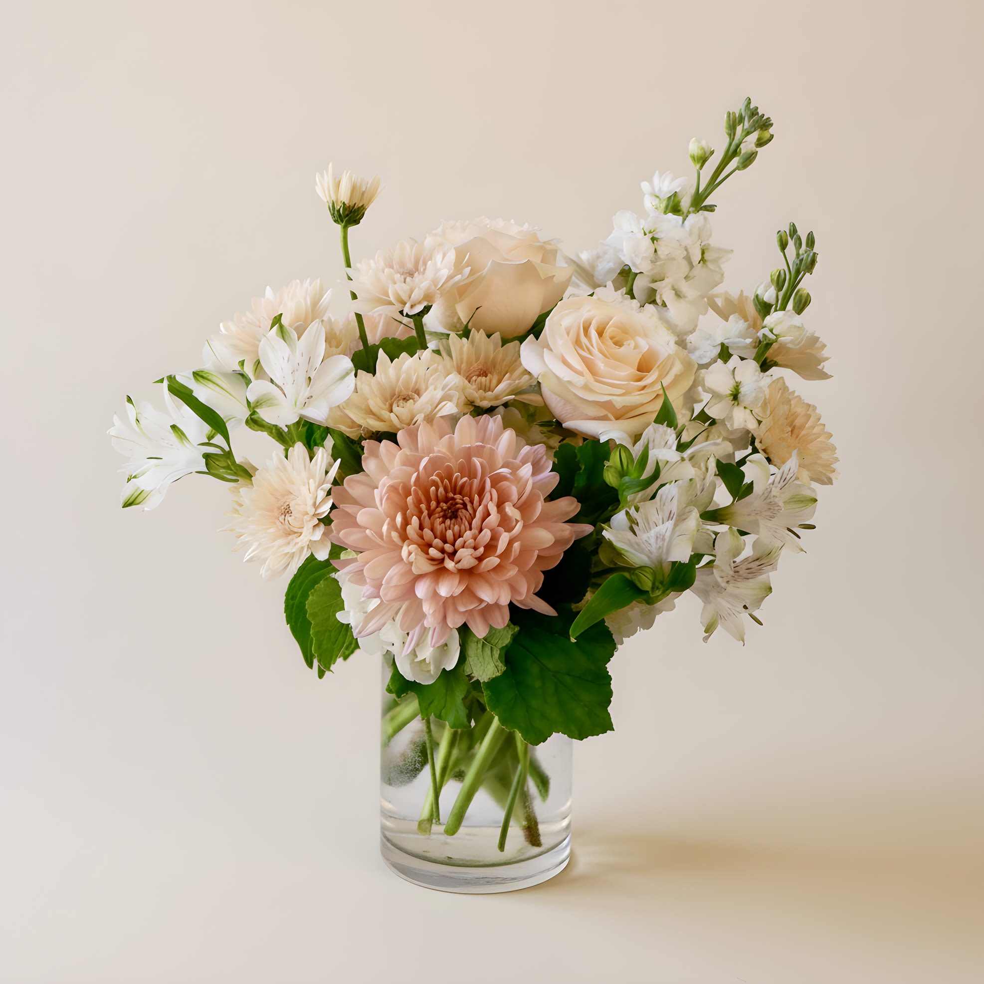 Honey Silk - Honey Silk is a soft and sophisticated flower arrangement featuring a timeless blend of warm neutrals and fresh white blooms. This elegant design includes peach roses, creamy chrysanthemums, white hydrangea, alstroemeria, stock, and fresh eucalyptus — all artfully arranged in a 4x6" clear glass vase. Perfect as a centerpiece or gift for birthdays, anniversaries, or sympathy occasions, this neutral-toned floral arrangement complements any home or office decor. A beautiful option for anyone seeking a modern, minimalist flower arrangement with classic charm. Arrangement approximately measures 15" tall and 13" wide with flowers.