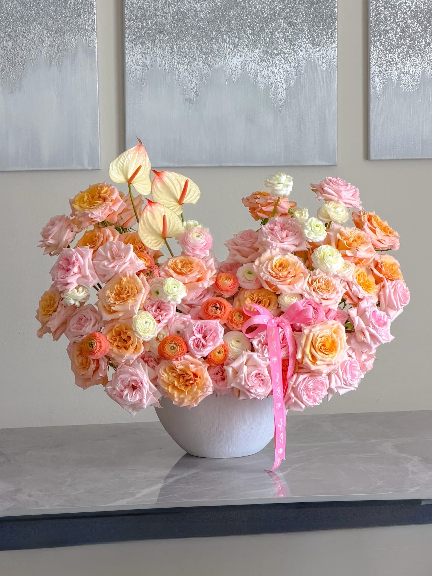 Blush Dream  - A lush, rounded arrangement in soft blush, peach, cream and pale orange-perfect as an anniversary bouquet, birthday surprise, or wedding gift that reads romantic and celebratory. Packed with garden-style roses and layered ranunculus, the composition has a full, petal-rich look that makes the recipient feel seen and adored the moment they set eyes on it. The arrangement is large and abundant-a memorable way to mark anniversaries, weddings, birthdays, or any moment when you want someone to feel truly celebrated.