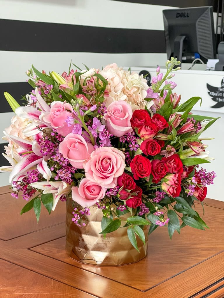 Pink and red roses with lilies in a gold vase