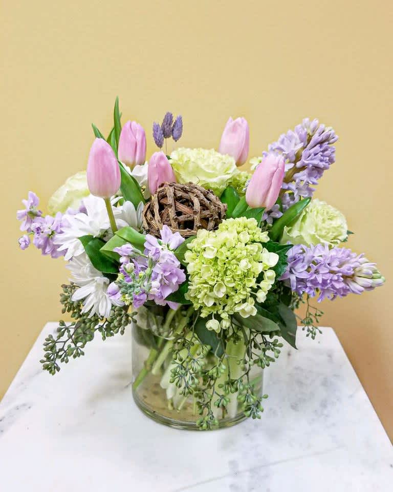 Pink tulips and lavender flowers arranged in a glass vase