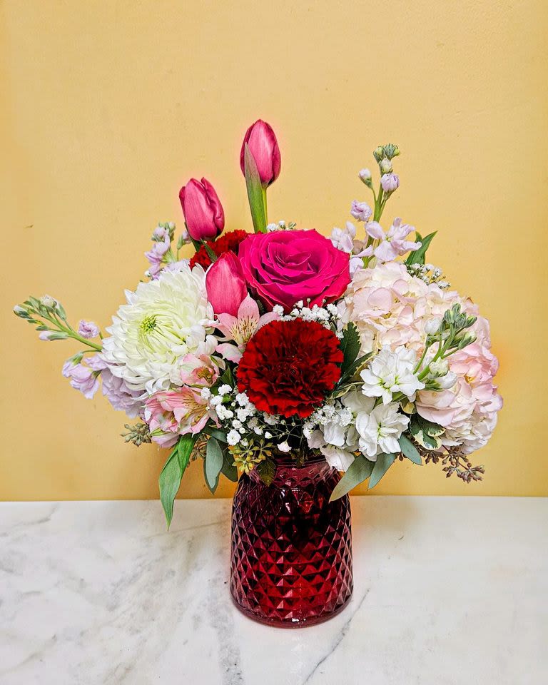 Mixed bouquet of pink and white flowers in a red glass vase