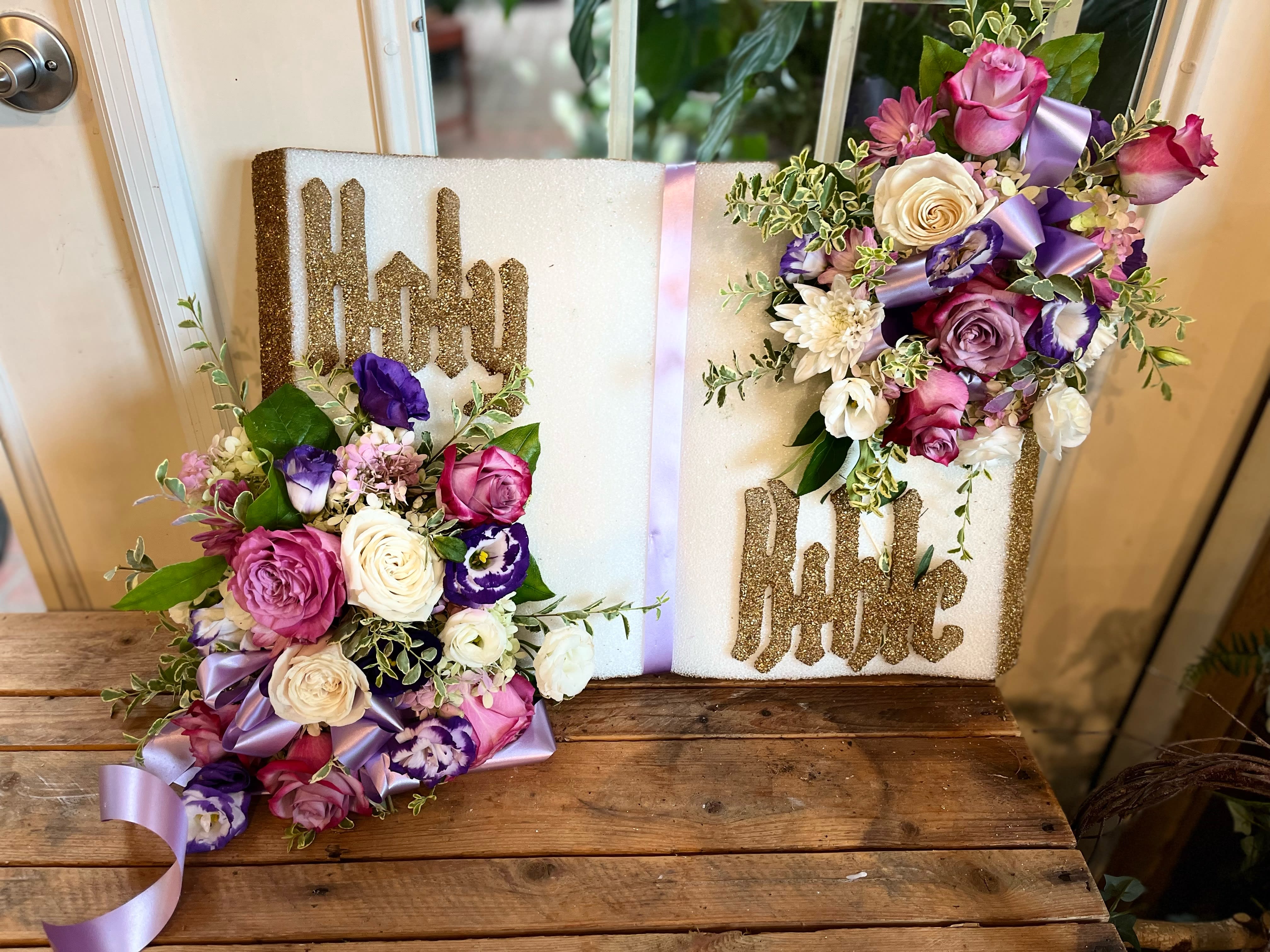 Religious book-style floral tribute with pink, white, and purple blooms on a Holy Bible plaque