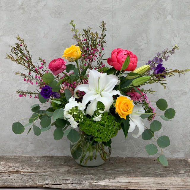 Mother's Day Amore Mere - The season's most beautiful blooms designed in a garden style in a clear glass vase. *We may substitute flowers due to availability, but we will maintain the overall color palette and design* 