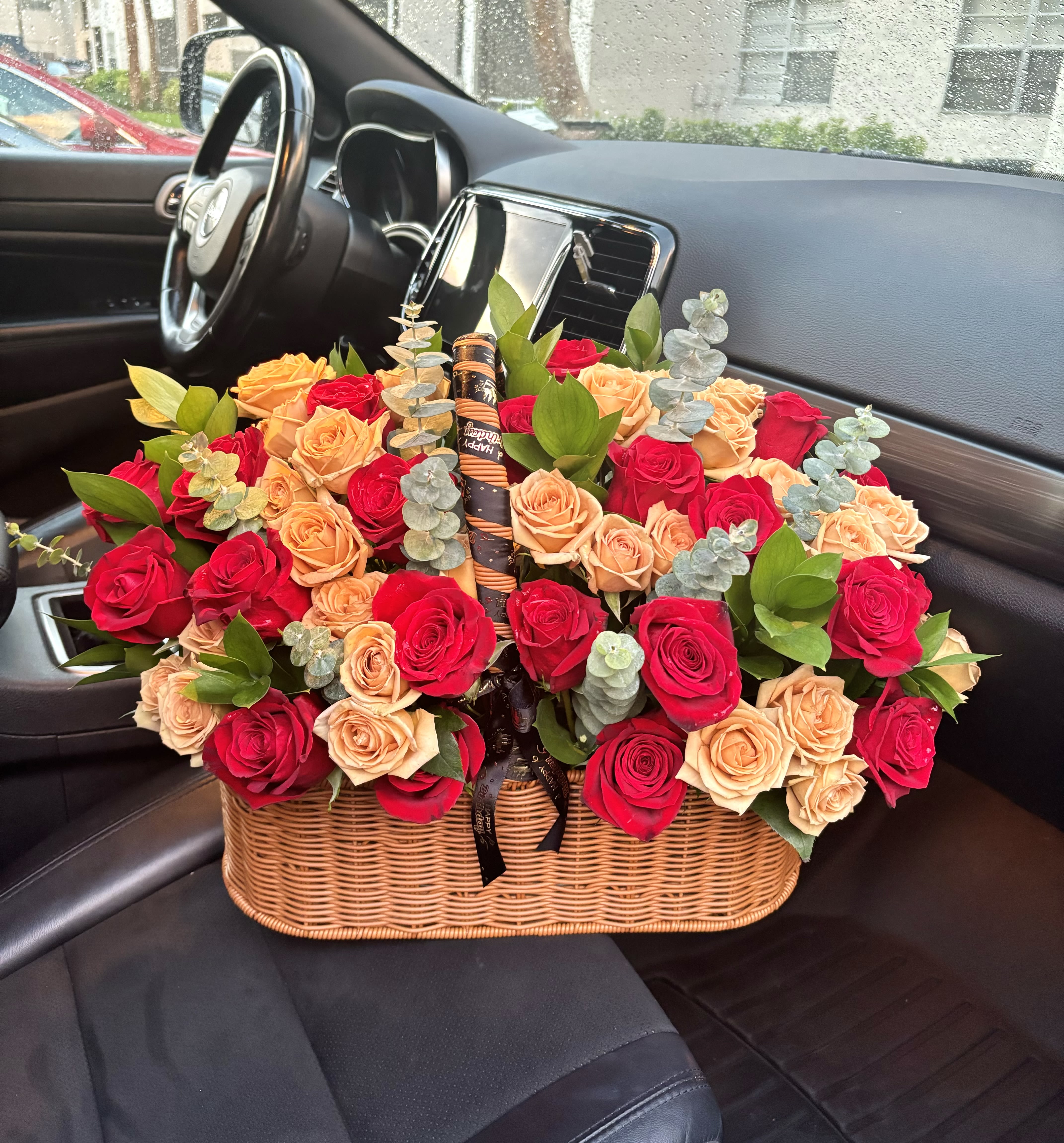 Basket of red and peach roses with eucalyptus in a car seat