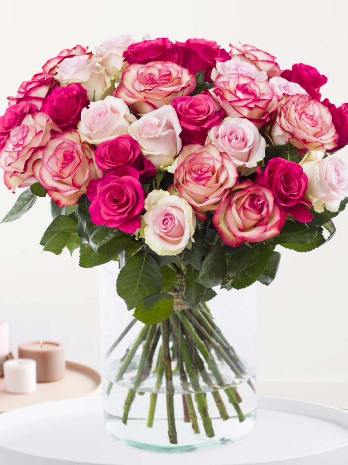 Soft Love Roses - A lush cluster of pink, blush, and white roses creates an instantly romantic birthday bouquet or anniversary arrangement that reads as soft and feminine at first glance. This flower arrangement-perfect for saying "I love you," "thank you," or "I'm thinking of you"-gives the recipient a classic, celebratory impression with a modern, tightly rounded silhouette.  The design features layered roses in vivid pink, blush and creamy white tones, arranged tightly so the blooms sit full and abundant. Long stems are visible in a clear glass vase that lets the stems and water show through, keeping the look clean and timeless while supporting the rounded shape. Sized for everyday gifting, this arrangement brings fragrant rose texture and a soft color palette ideal for mothers, partners, friends, or anyone who deserves a warm, elegant surprise.