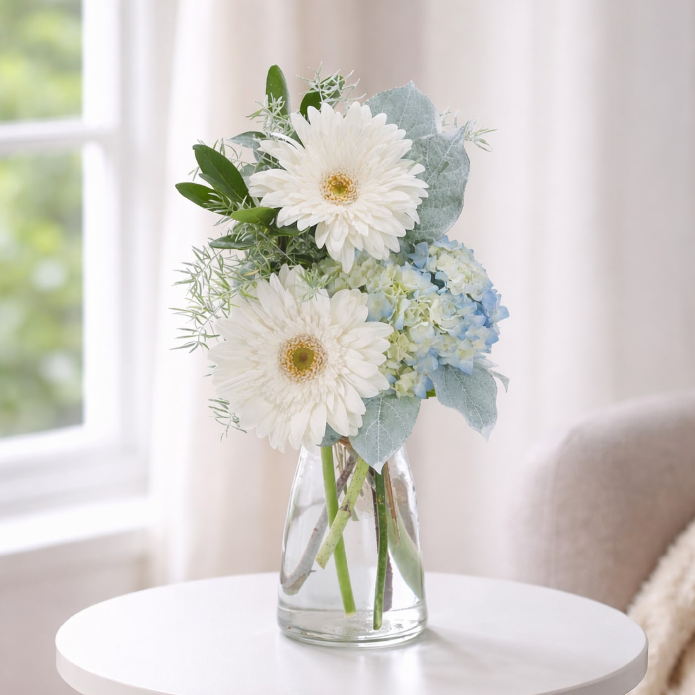 Blue Mist - Soft blue and white blooms arranged in a clear vase for a simple misty look.