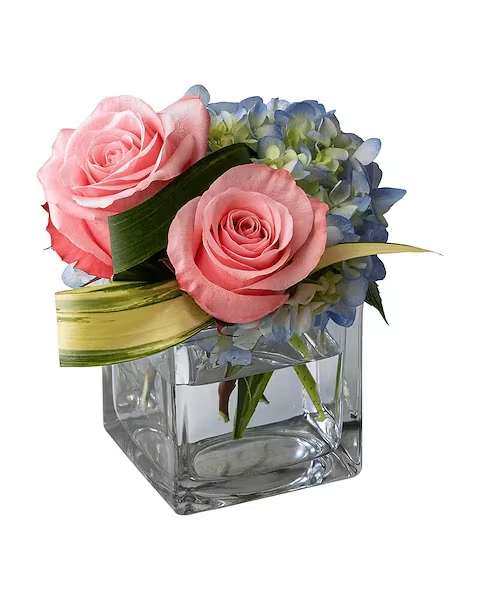 Pink roses and blue hydrangeas in a clear square vase