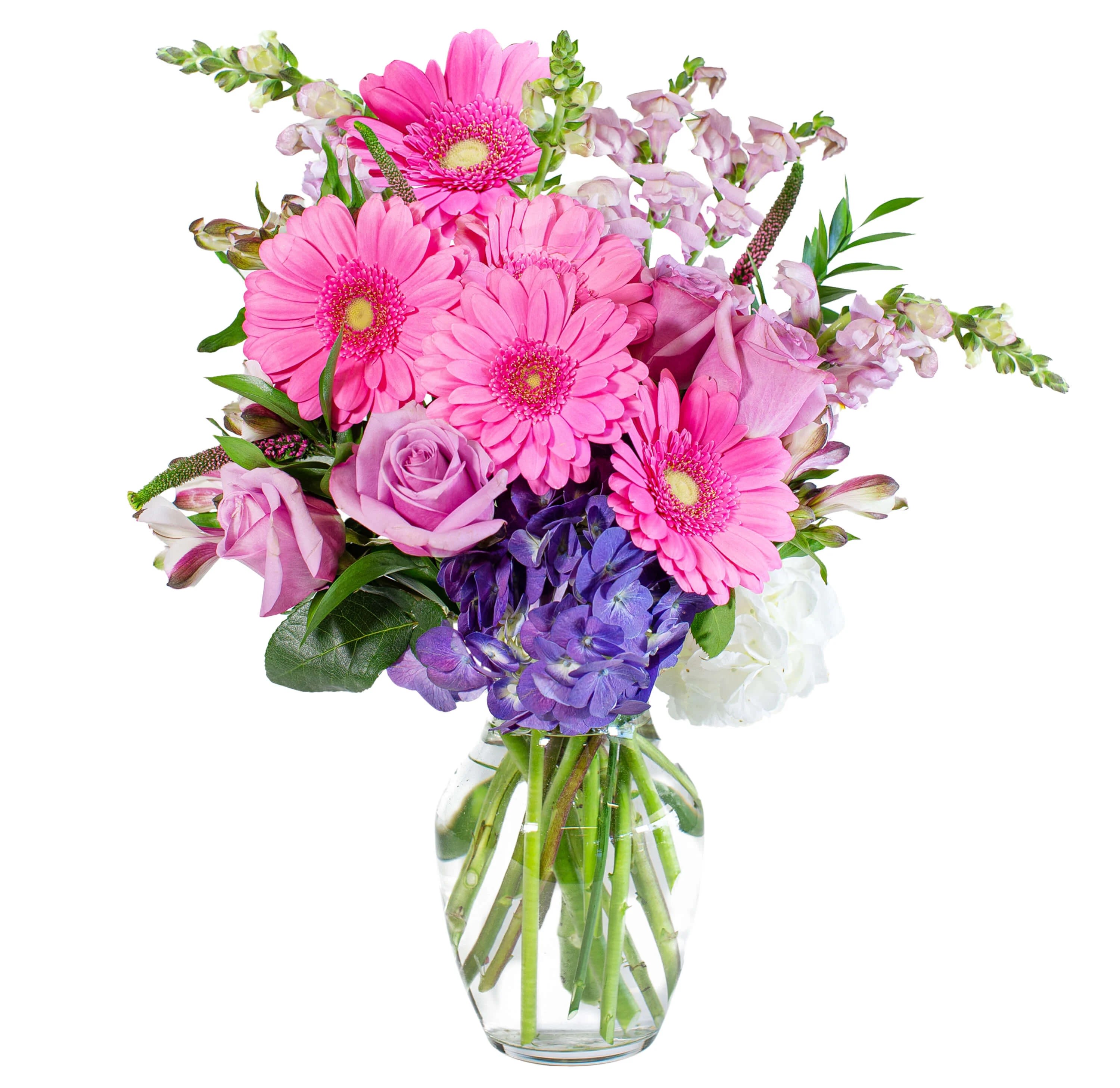Mixed bouquet of pink gerbera daisies, lavender roses, and purple hydrangeas in a clear glass vase