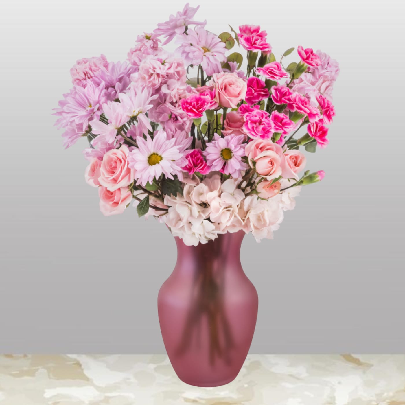 Pink bouquet of roses, carnations, and daisies in a frosted mauve glass vase