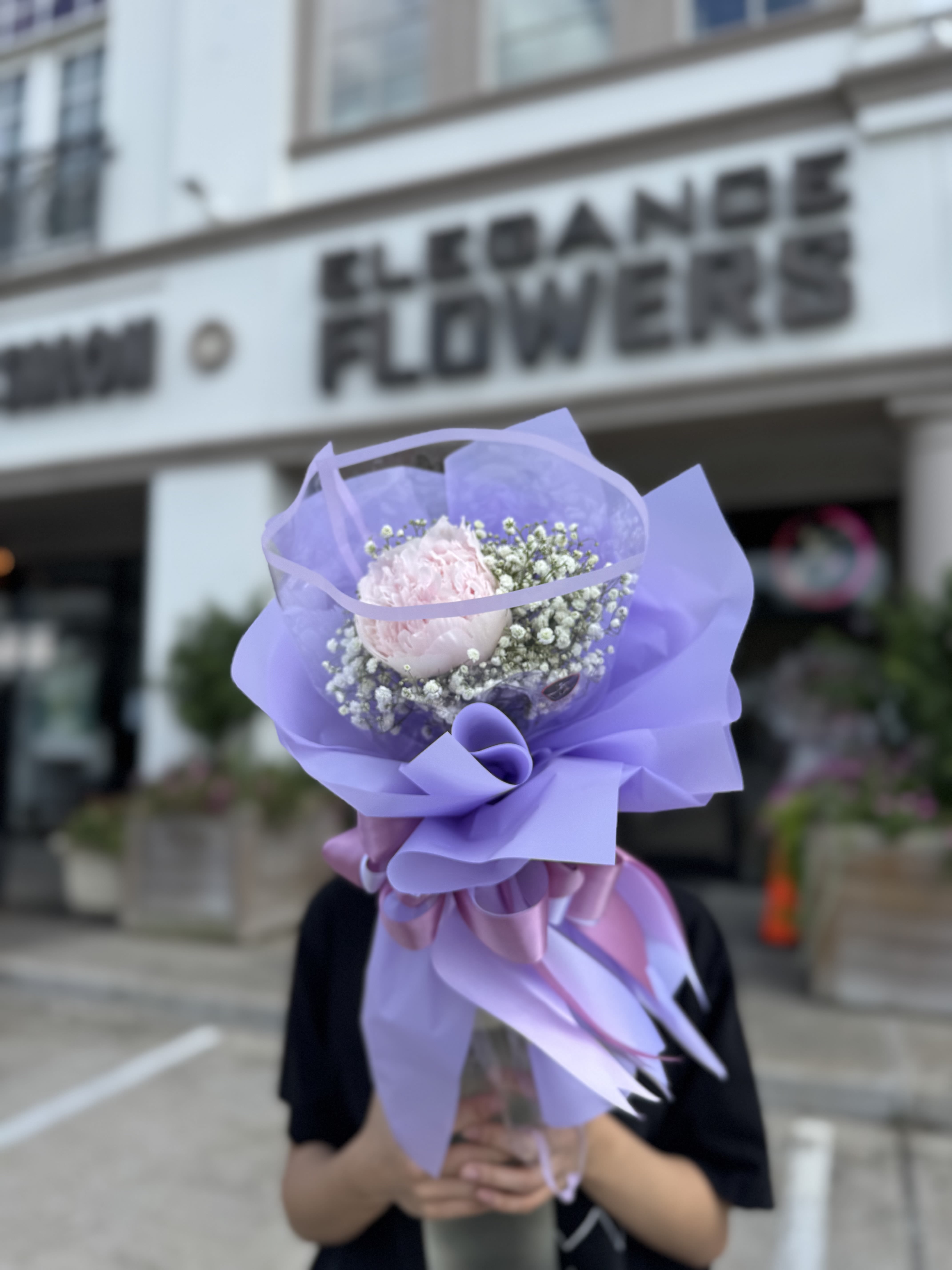 Lavender-wrapped bouquet with a pale pink bloom and baby's breath