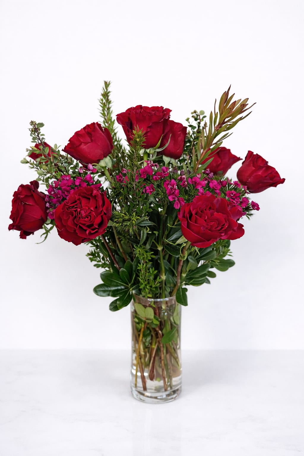 Red roses and pink filler flowers in a clear glass vase