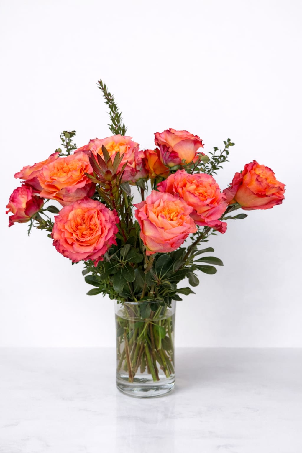 Orange-pink roses arranged in a clear glass vase