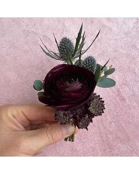 Purple Hues Boutonniere - All of our boutonnieres include multiple blooms with touches of greenery. Each boutonniere is wrapped in a thin tie of silk ribbon and two boutonniere pins are included.