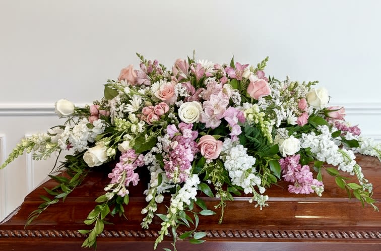 Pink and White Casket Spray  - A beautiful mix of pink and white flowers that lay across the middle or end section of a casket. Varieties include roses, snapdragons, spray roses, alstroemeria, daisies, and stock. With flowing greenery this makes a soft and beautiful tribute to your loved one. 