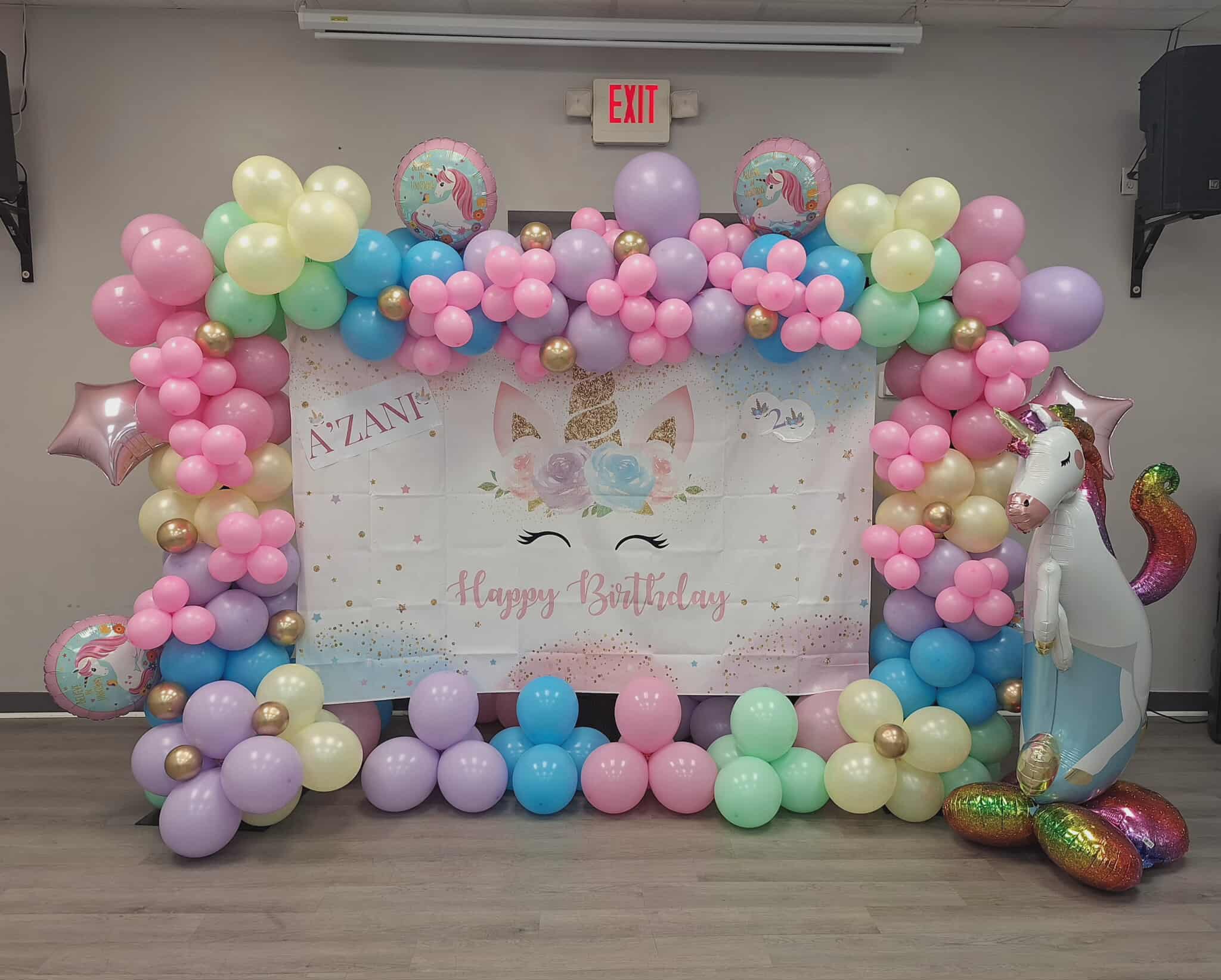 Pastel balloon arch with unicorn birthday backdrop and foil unicorn balloons