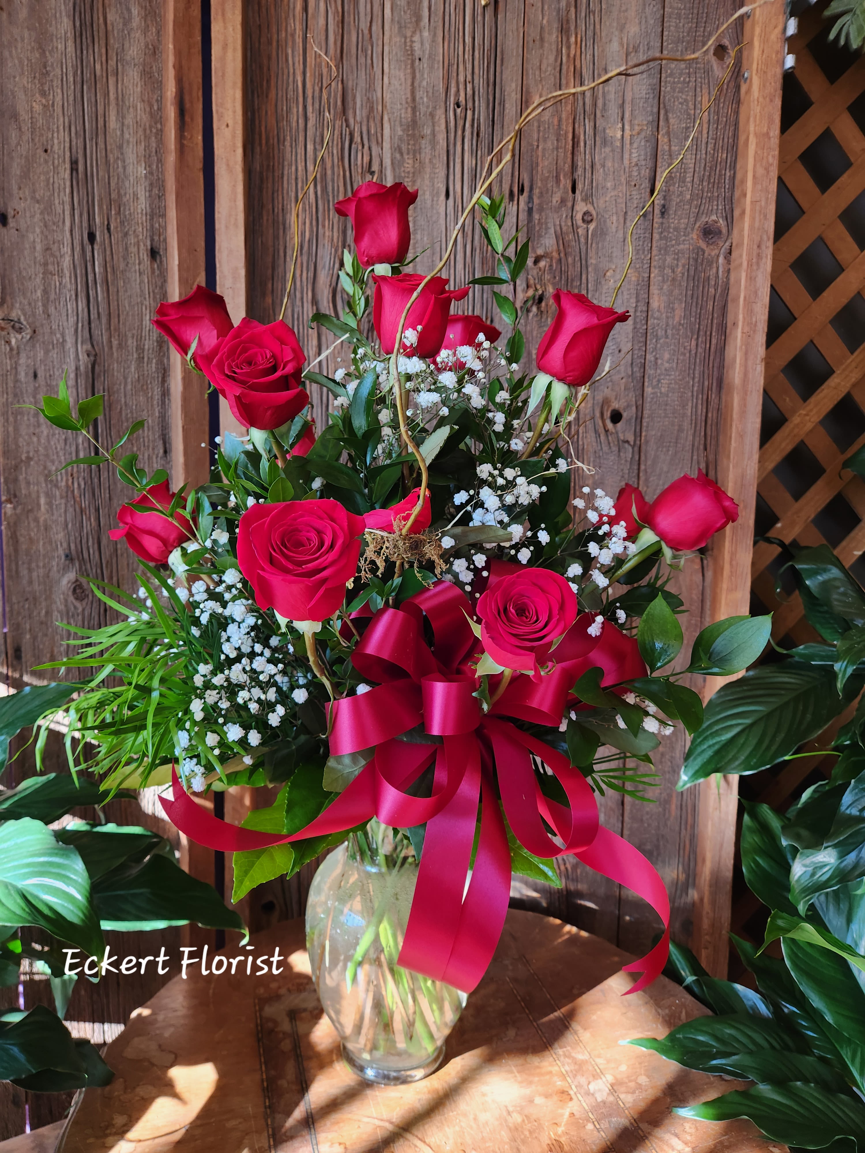 Red roses arranged in a clear glass vase with a red ribbon bow