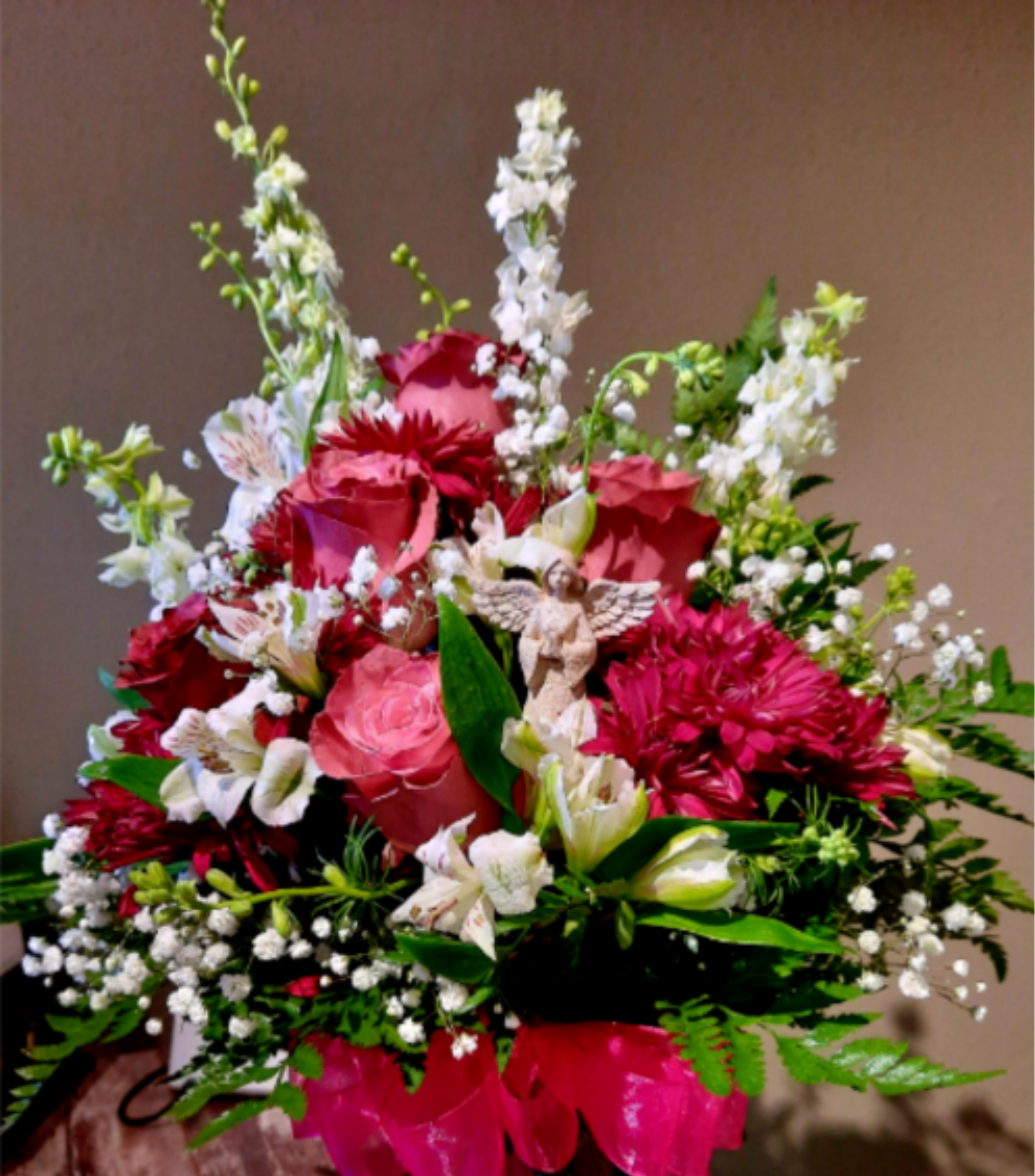 Pink and white mixed flower arrangement with a small angel figurine