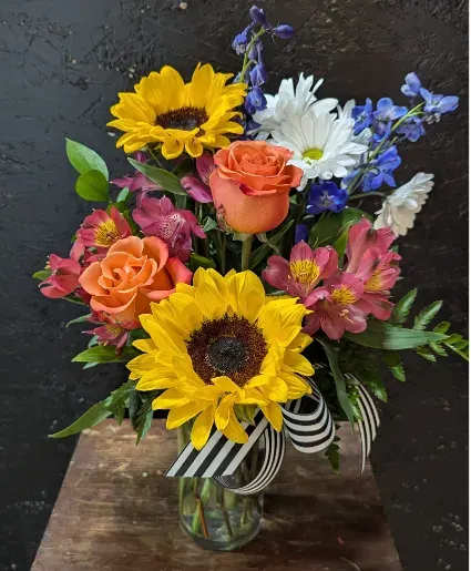 A Nice Surprise - Cylinder vase includes sunflowers, roses, delphinium, alstroemeria and daisy mums