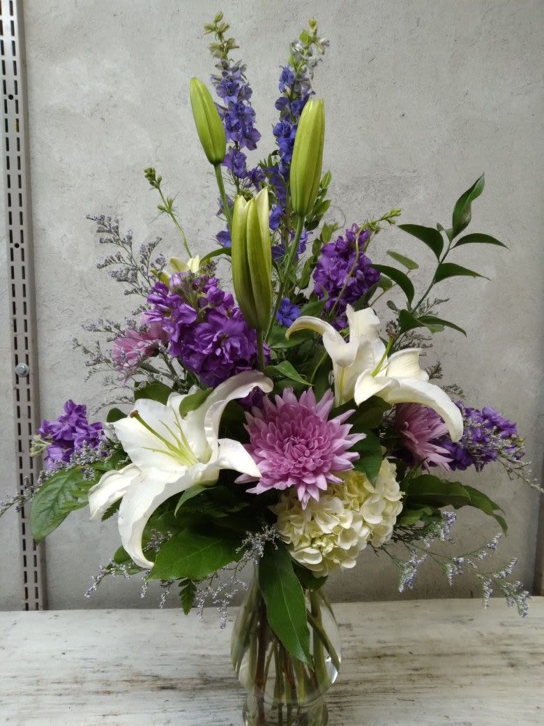 Serene Grace Arrangement - This vertical arrangement is a sophisticated blend of stately white blooms and rich purple textures, and brings a certain kind of elegance to any occasion or room.