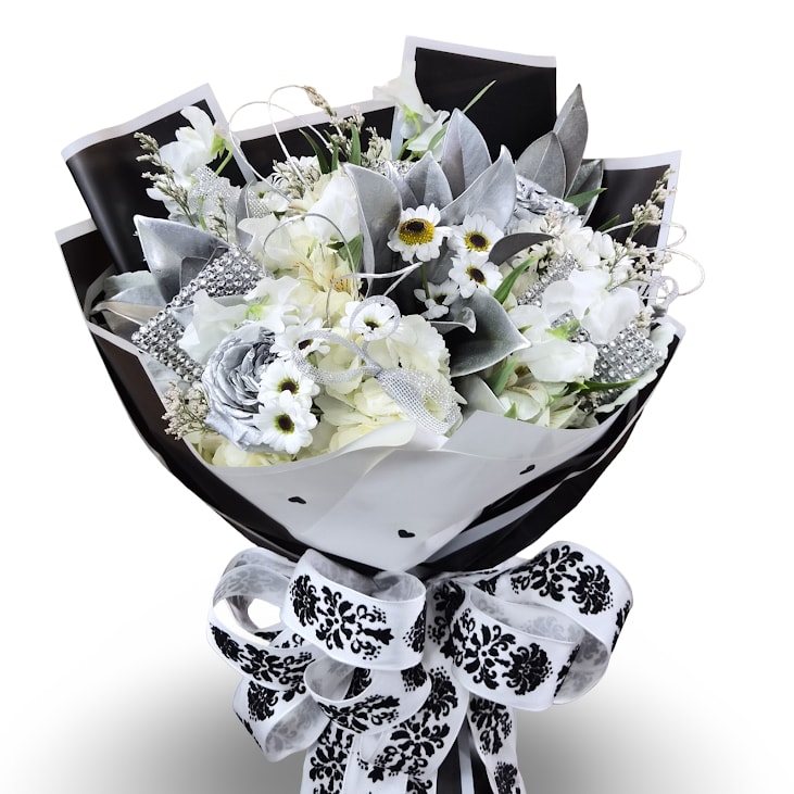 Diamonds &amp; Daisies Cellowrap - White daisies, lush white hydrangea clusters, and elegant lily blooms are arranged in a full, rounded bouquet that reads modern and refined-perfect as a birthday bouquet, thank-you arrangement, or a tasteful sympathy offering. Perfect to celebrate a birthday in April with Diamonds and daisies as the birth stone and birth flower.  The arrangement is cellowrappped in black decorative paper and finished with an ornate white ribbon for a polished presentation. This arranged does not come with a vase, but comes wrapped in a wet sponge that will last a few hours. 