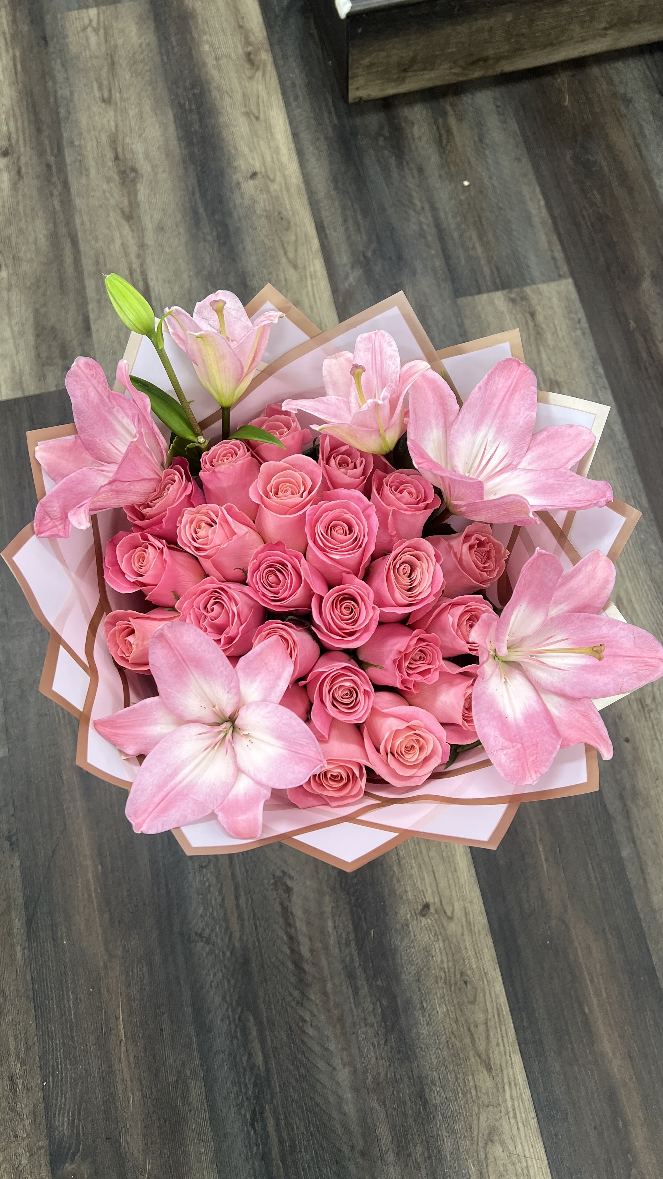 Pink rose bouquet with large pink lilies wrapped in white and tan paper