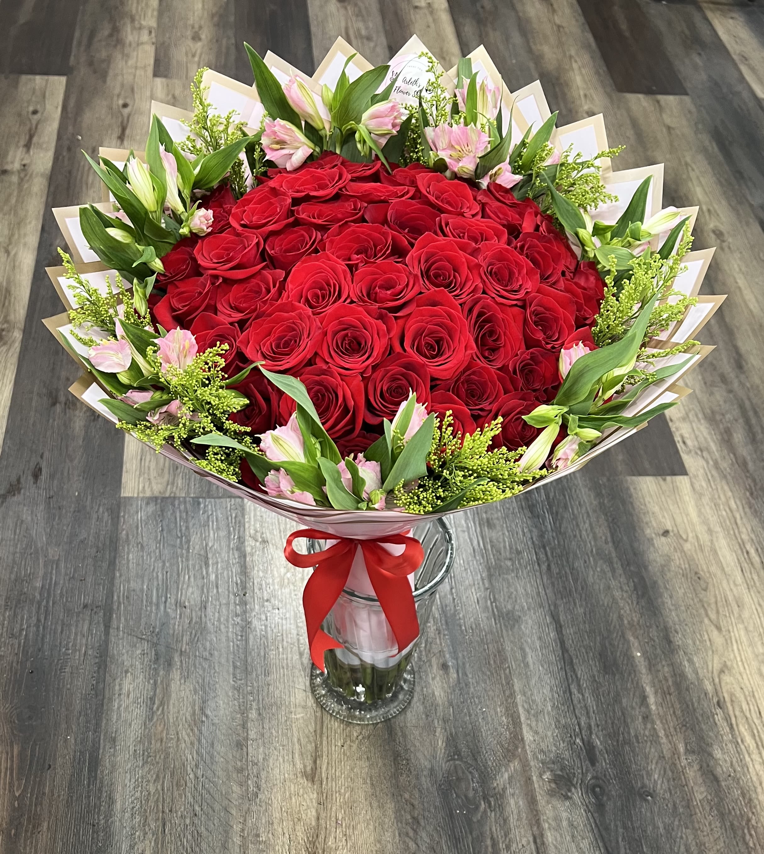 Bouquet of red roses with pink lilies in a glass vase