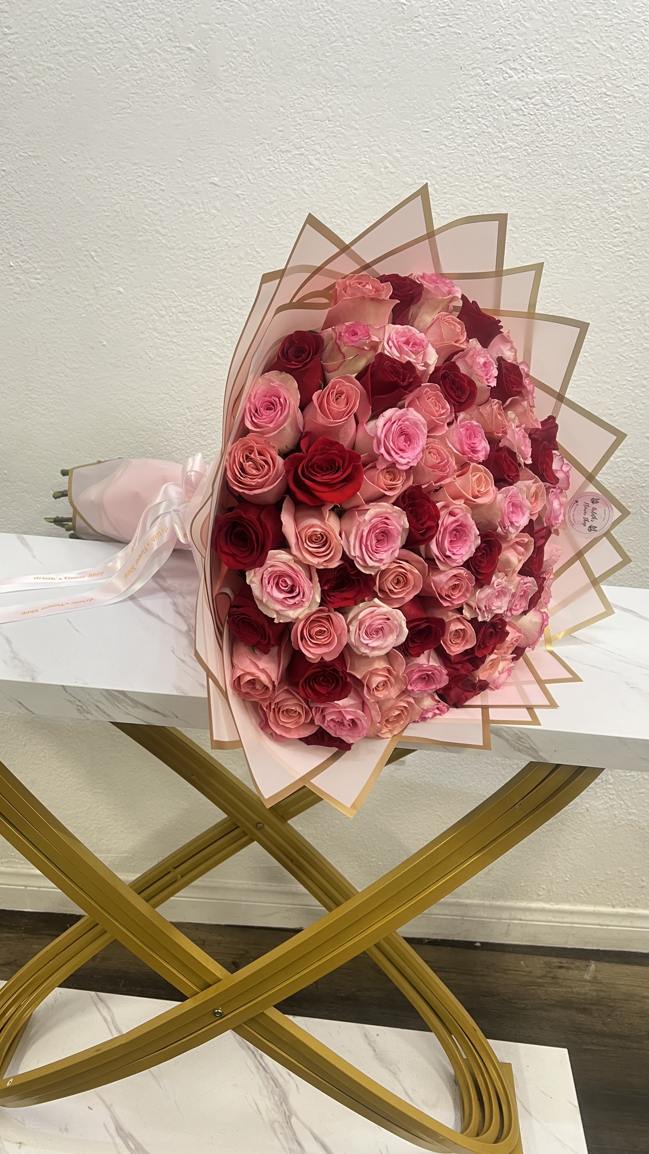 Large bouquet of pink and red roses wrapped in blush paper